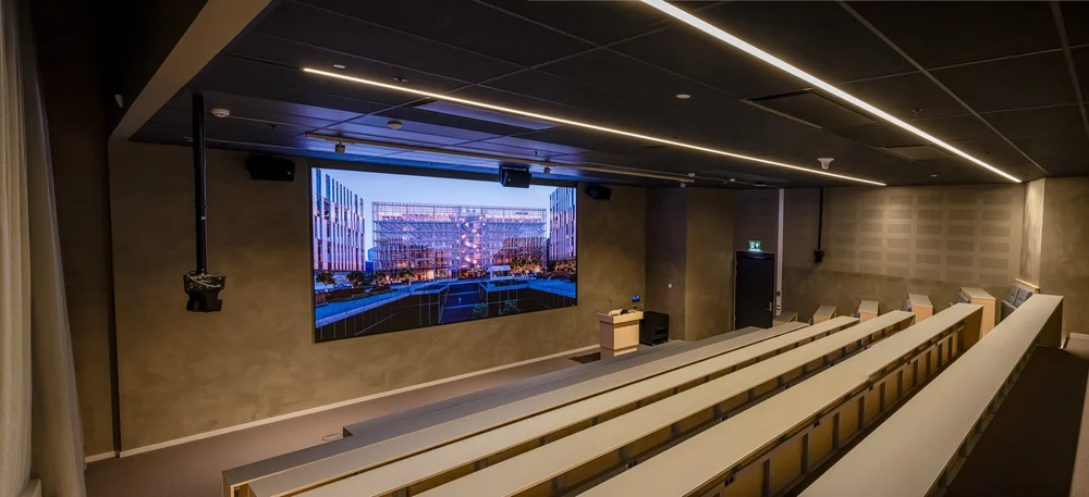 Auditorium med trappetrinnstoler og skjerm
